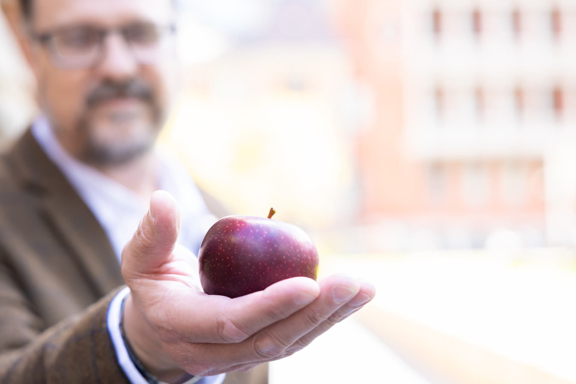 Juan offering a red apple in his palm