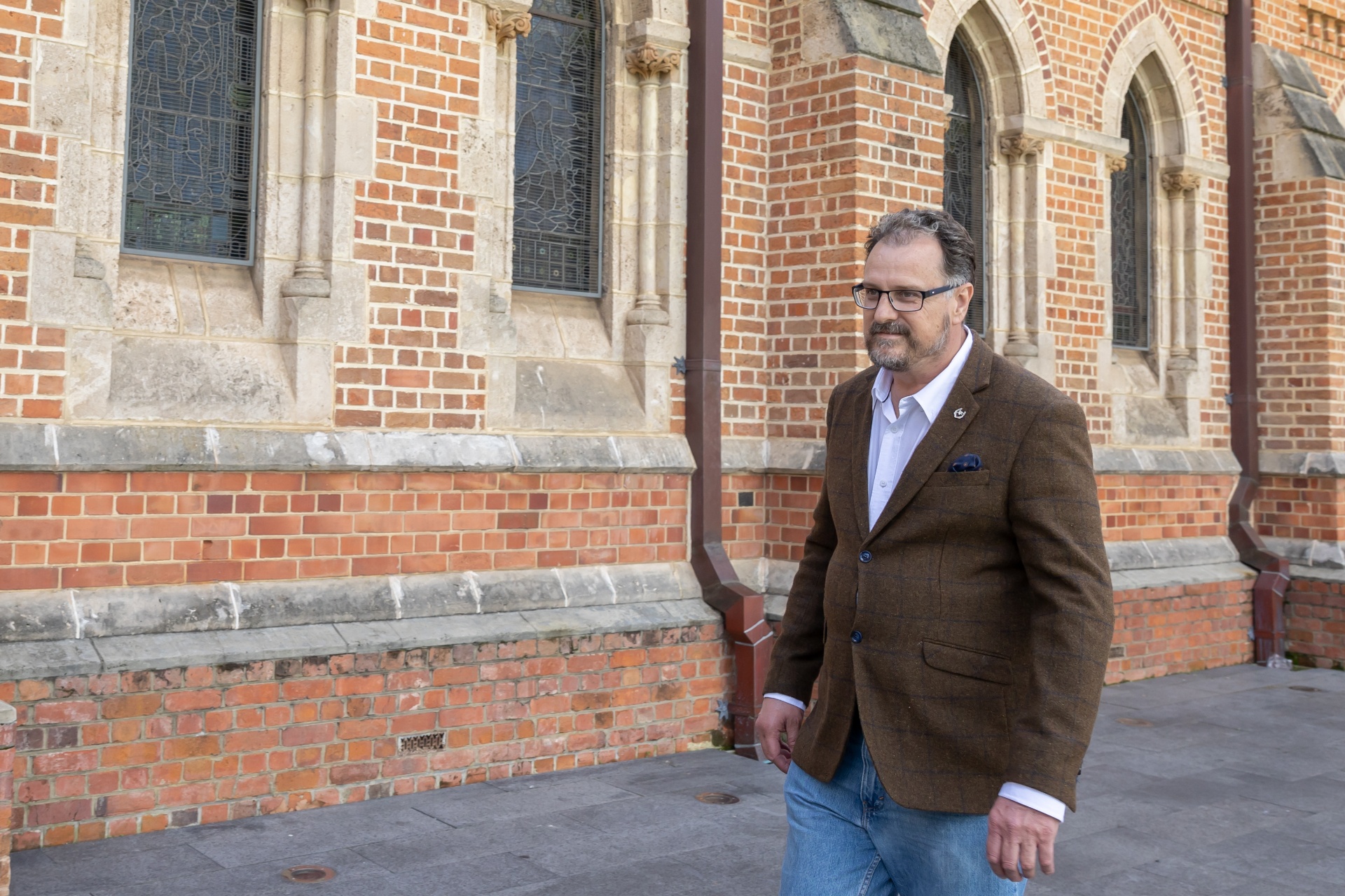 Juan walking past a cathedral wall in Perth