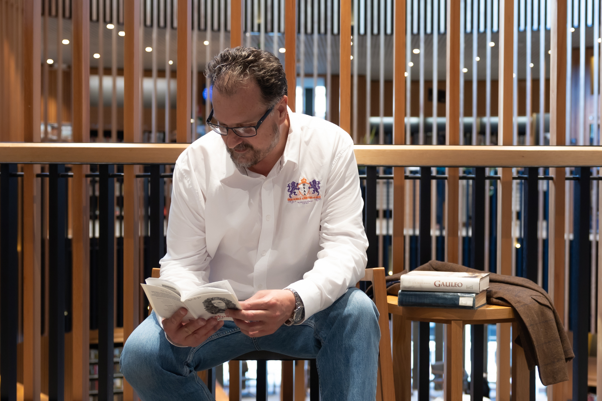 Juan reading in a library beside a stack of books including a biography of Galileo
