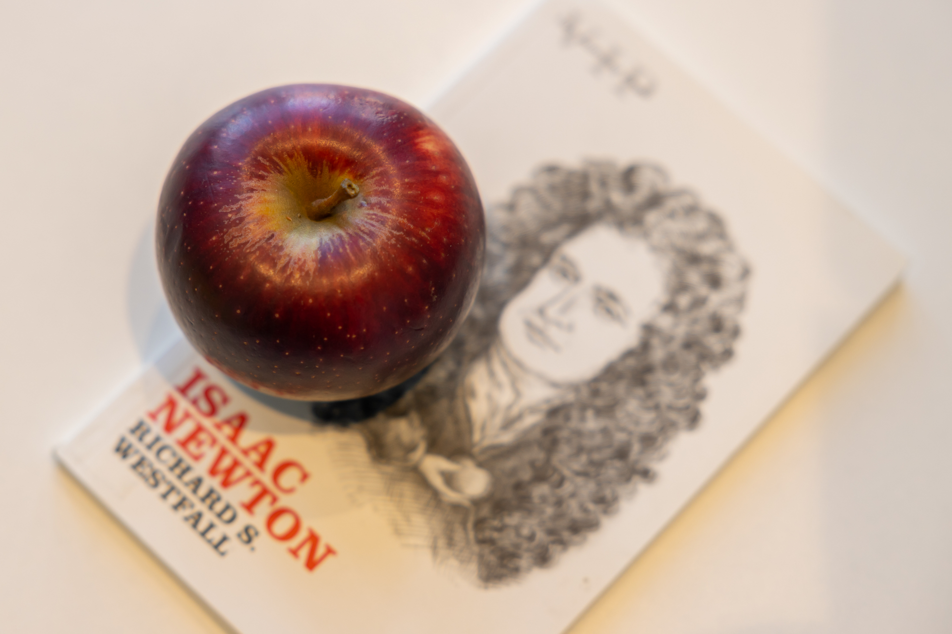 A red apple sitting on a biography of Isaac Newton